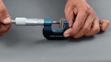 El ele tutuşan analog mikrometre ya da diff mikrometre kalite kontrol tüpü gri masanın üzerinde. Vida ölçer kalibreleri analogu kullan. kalite kontrol kavramı.