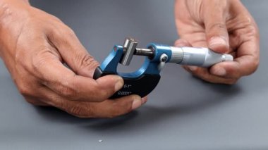 El ele tutuşan analog mikrometre ya da diff mikrometre kalite kontrol tüpü gri masanın üzerinde. Vida ölçer kalibreleri analogu kullan. kalite kontrol kavramı.