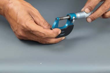 El ele tutuşan analog mikrometre veya diff mikrometre, mikrometre dışındaki ayarlama gri arkaplan üzerinde.