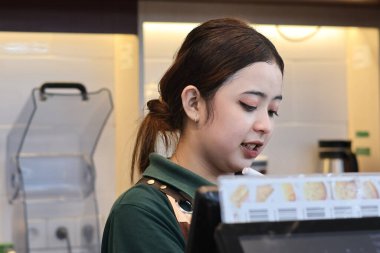 Balikpapan-Endonezya 22 Mayıs 2025 Güzel Asyalı bayan barista kahve makinesiyle Endonezya 'nın İndomaret bölgesinde çalışıyor..