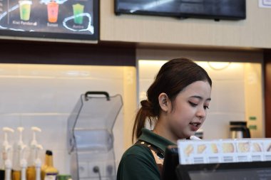 Balikpapan-Endonezya 22 Mayıs 2025 Güzel Asyalı bayan barista kahve makinesiyle Endonezya 'nın İndomaret bölgesinde çalışıyor..