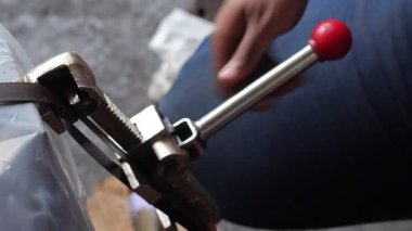 Paketlerin elle bağlanması, metal şeritleri germek için bir cihaz kullanarak elinizi kapatın. Kutuları ve paletleri bağlamak için araç.