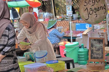 Balikpapan-Endonezya 29 Mayıs 2025 Geleneksel Cava kıyafetleriyle (Cava şapkası) Geleneksel bir gıda satıcısı geleneksel bir pazarda müşterilere hizmet veriyor