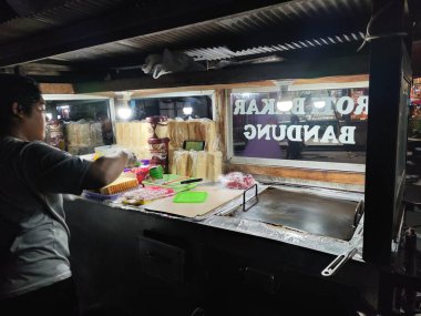 9 Haziran 2025 'te Balikpapan-Endonezya' da yol kenarındaki bir tost satıcısı çubuksuz çelik bir tost tavasında ekmek pişiriyor. Roti Bakar Bandung Endonezya 'da popüler bir sokak yemeği.