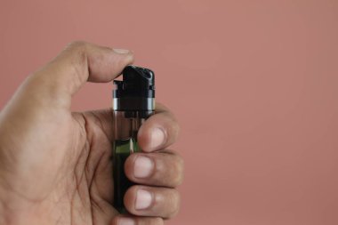 Balikpapan-Indonesia June 20, 2025 Hand holding a lighter and ready to light up, isolated on brown background.