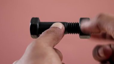 Kara cıvatayı tutan eli kapat ve cıvatalı vidayı gevşet izole arka planda.