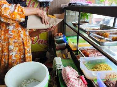 Balikpapan-Endonezya 20 Haziran 2025. Nasi Campur satıcısı alıcılara servis yapıyor, Nasi Campur satıcısı müşterilerin siparişlerini paketliyor..