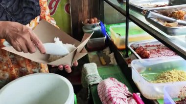 Balikpapan-Endonezya 20 Haziran 2025. Nasi Campur satıcısı alıcılara servis yapıyor, Nasi Campur satıcısı müşterilerin siparişlerini paketliyor..