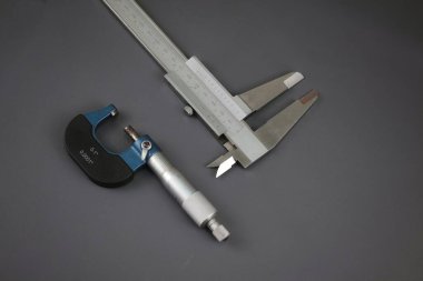 Gri arka planda mekanik vida mikrometresi ve vernier kalibre yakın çekim. Vintage ölçüm aleti. El aracı