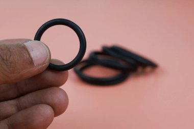 Pembe arka planda farklı boyutlarda izole edilmiş parmak üzerinde O halkası veya lastik conta kapatın. Hidrolik ve pnömatik konsept