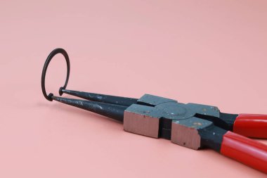 Plier 'ı kapat ve kahverengi arka planda izole edilmiş bir şekilde halka veya daire şeklinde çember çiz. Kerpetenin ucundaki halka.