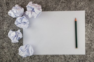 Üst görünüm boş kağıt, kalem ve birkaç buruşuk kağıt topu masanın üstünde fikir bekliyor..