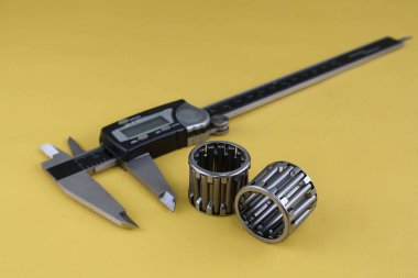 Dijital vernier kalibreli ve sarı arka planda dönen silindirli. Dış ve iç boyutların yüksek hassasiyetli ölçümleri için evrensel araç. Ölçüm aracı.