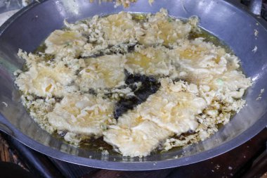 Satıcı alıcıları geleneksel pazarda kızartıp servis ediyor. Kızartma temposu işleniyor. Endonezya yemekleri.