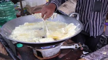 Satıcı alıcıları geleneksel pazarda kızartıp servis ediyor. Kızartma temposu işleniyor. Endonezya yemekleri.