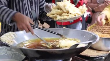 Satıcı alıcıları geleneksel pazarda kızartıp servis ediyor. Kızartma temposu işleniyor. Endonezya yemekleri.