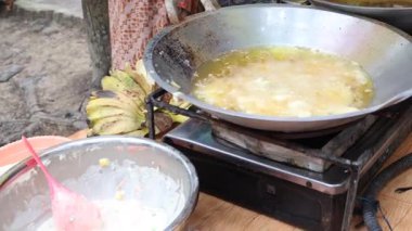 Satıcı alıcıları geleneksel pazarda kızartıp servis ediyor. Kızartma temposu işleniyor. Endonezya yemekleri.