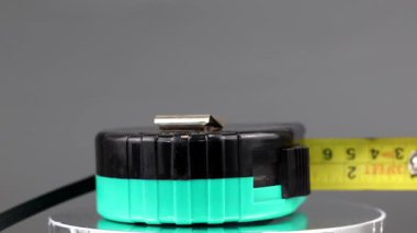 Dönen ekranda ölçü bandı. Siyah, toska renkli ve sarı bantlı mezura..