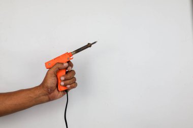 Erkek el ele tutuşan turuncu lehim silahı beyaz arka planda izole edilmiş. Lehim araçları. 
