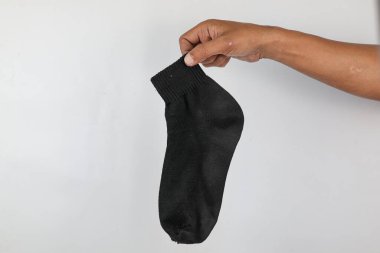 Erkek el ele tutuşan siyah çorap beyaz arka planda izole edilmiş. Çorap kokusu konsepti..