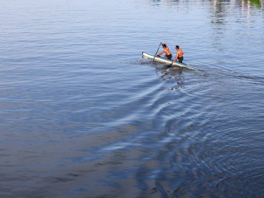 İki adam Manggar Nehri 'nde bir kanoda kürek çekiyor. Genç arkadaşlar güneşli bir yaz gününü kano gezisine giderek geçirirler.