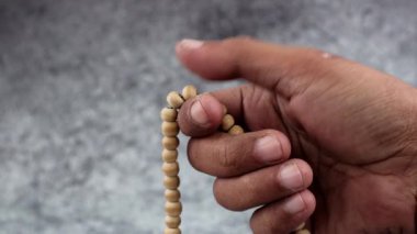 Arkaplanı bulanık olan dua boncuklarıyla dhikr okuyan elleri kapatın. Dzikir el