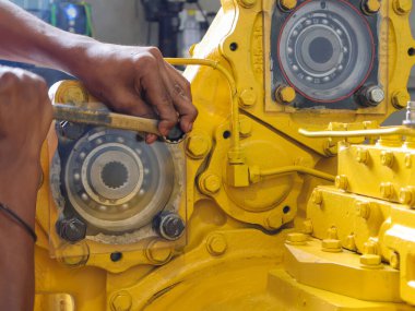 Balikpapan-Endonezya 5 Ağustos 2025 Tamircinin elini kapatın Komatsu 8250 'nin sarı şanzıman cıvatasını yüzük anahtarıyla sıkılaştırın.