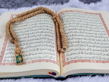 Balikpapan-Endonezya 5 Ağustos 2025 Kutsal Kur 'an' ın Arapça el yazısı ve tasbih ya da beyaz kadife kumaş üzerinde tespih anlamına gelir..