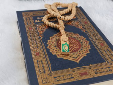 Balikpapan-Endonezya 5 Ağustos 2025 Kutsal Kur 'an' ın Arapça el yazısı ve tasbih ya da beyaz kadife kumaş üzerinde tespih anlamına gelir..