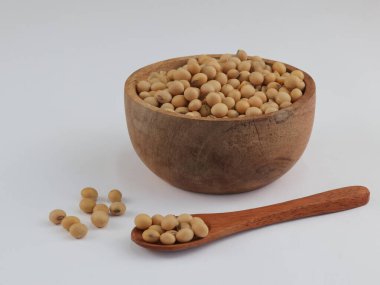 Beyaz arka planda izole edilmiş tahta kasede soya fasulyesi tohumları..