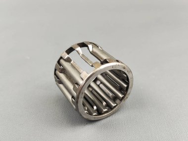 Gri bir yüzeyde bir iğne rulosunun hasar görmesi görülür. Fotoğraf endüstriyel kısmın mekanik hassasiyetini ve metalik dokusunu vurguluyor..