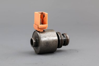 Katı gri arka planda duran turuncu plastik konnektörlü metal bir solenoid valf. Allison İletim solenoidi 
