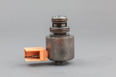 Katı gri arka planda duran turuncu plastik konnektörlü metal bir solenoid valf. Allison İletim solenoidi 