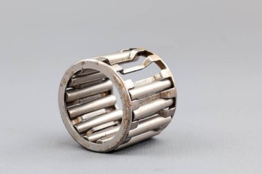 Gri bir yüzeyde bir iğne rulosunun hasar görmesi görülür. Fotoğraf endüstriyel kısmın mekanik hassasiyetini ve metalik dokusunu vurguluyor..