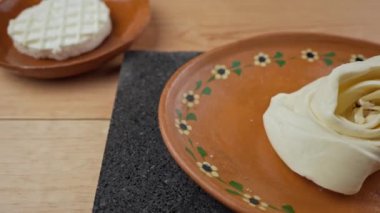 Oaxaca peyniri ya da quesillo ve killi tabakta yuvarlak peynir.