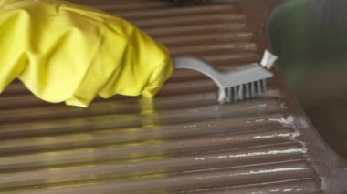 Tel fırçayla mutfakta tartar temizleyen bir kadın.