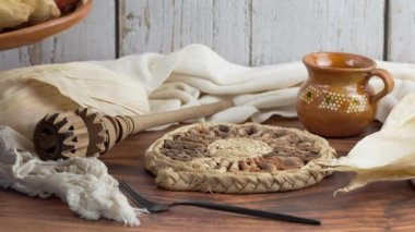  Latin kadın masaya farklı tatlarda tamale içeren geleneksel bir kil tabağı koyar.