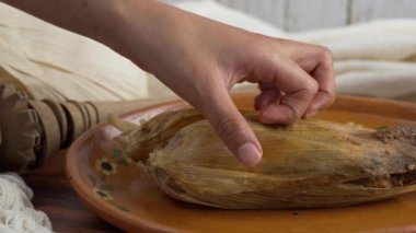 Latin kadın, Meksika yemeği Tamal de mole ile bir tamal paketini açıyor.