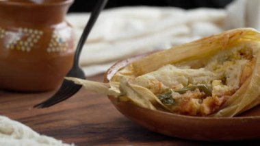 Meksikalı kadın bir parça baharatlı tamal aldı çatalla, Meksika yemeği Tamal de rajas