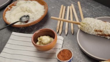 Kullanılan mayonez, yıllanmış peynir, kırmızı sos, kırmızı biber tozu ve tahta çubuklarla hazırlanmış mısır.