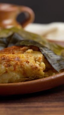 Dikey yemek videosu, tamal jarocho, domuz eti, kırmızı sos ve muz yaprağıyla sarılmış.