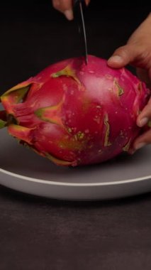 Dikey video, Latin bir kadının kadın elleri bir ejderha meyvesini ikiye bölüp meyvenin içini gösteriyor.
