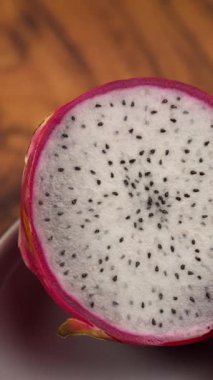 Dikey video, bir ejderha meyvesinin makro görüntüsü hamurunu göstererek ikiye bölünmüş, doğru seyahat çekimi