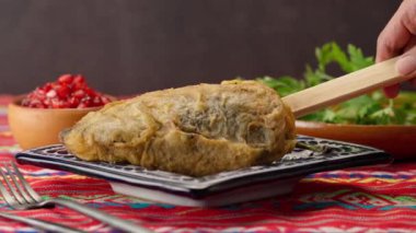 Meksikalı bir kadının eli Talavera poblana 'dan yapılmış bir tabağa süslenmemiş bir Şili koyar.