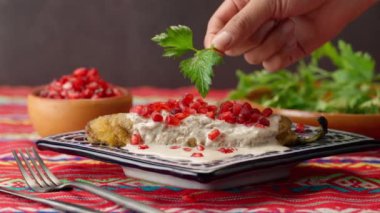 Bir kadının eli maydanoz yapraklarıyla bir Şili 'yi süslüyor