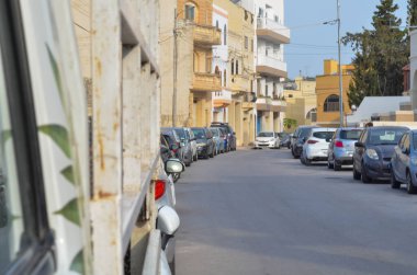 Sabahın erken saatlerinde sakin ve sakin bir şehir manzarası sunan, yumuşak, altın bir ışıkla yıkanmış boş bir sokak. Terk edilmiş yol, binalarla dolu.