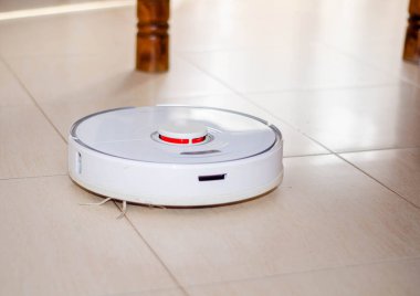 Görünür toz ve enkaz parçalarıyla döşenmiş fayanslı zeminde aktif olarak çalışan bir robot elektrikli süpürge. Zahmetsiz bir bakım deneyimi için akıllı temizlik teknolojisi..