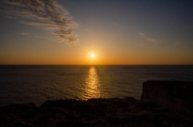  Uçsuz bucaksız okyanusun üzerinde çarpıcı bir günbatımı, gökyüzü ve su boyunca altın renkler döküyor. Güneşin yansıması huzurlu ve huzurlu bir atmosfer yaratır..