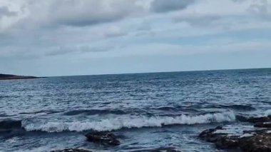 Deniz dalgalarının dinamik görüntüleri kıyıya çarpıyor, doğanın hareket halindeki sahil güçlerinin ham enerjisini ve güzelliğini gösteriyor..