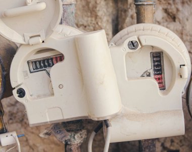 İki analog su taşıma sayacının, yerleşim yerinin su kullanımını izlemek ve tesisat altyapısını izlemek için kullanılan bir duvara monte edilmesinin ayrıntıları.